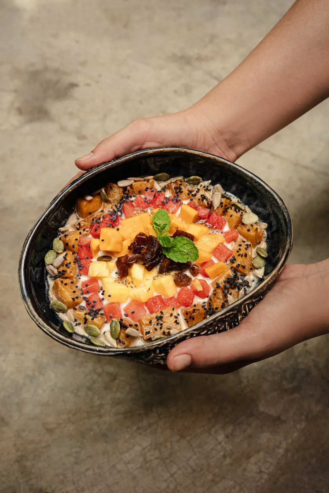 A fruit and granola bowl held out at Maha Mezze Cafe, Hiriketiya