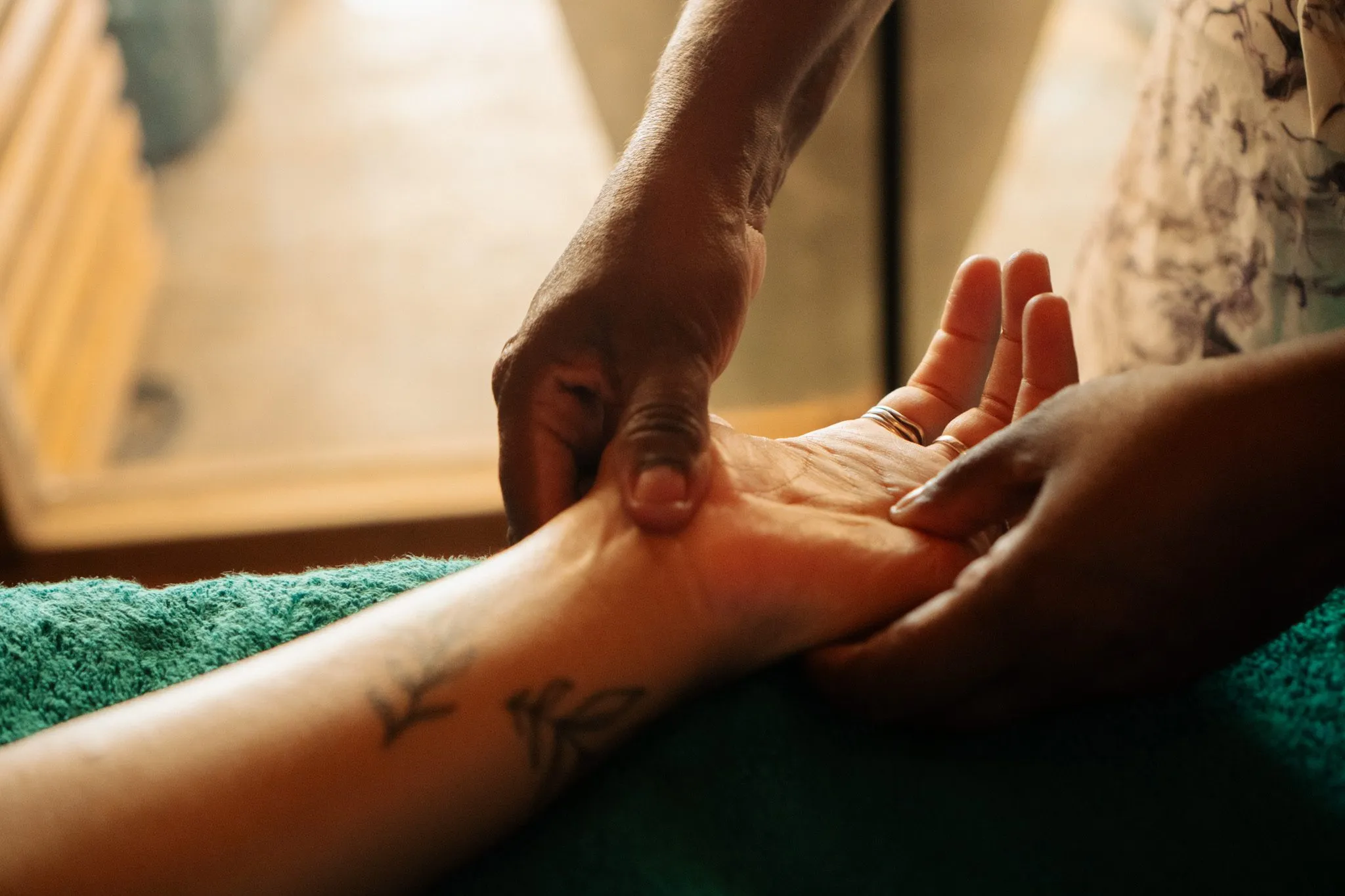 A therapist working on a guest's hand and wrist at Maha Sauna