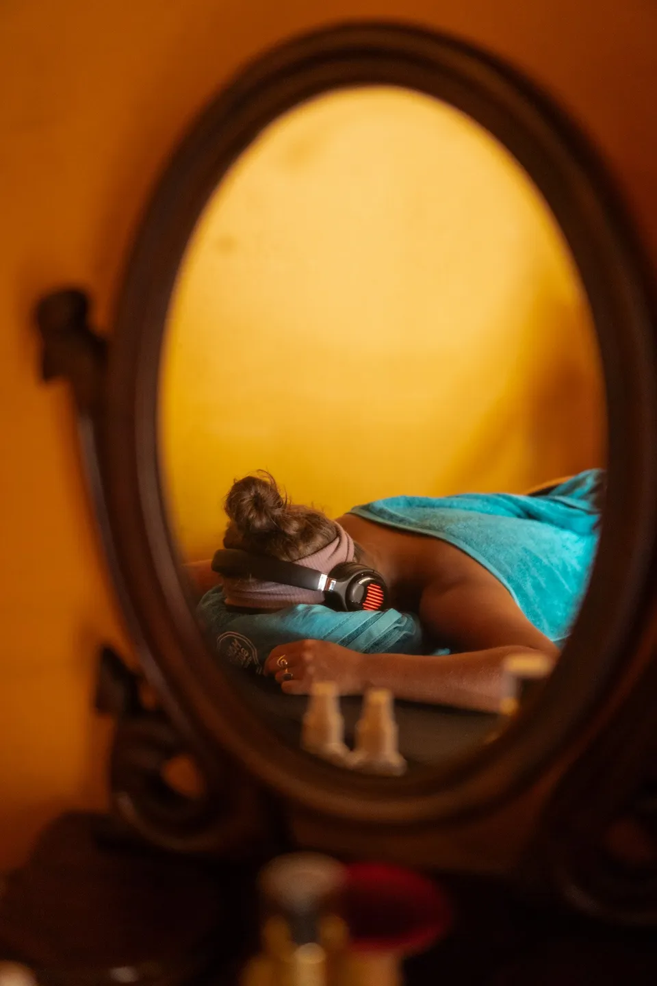 A guest resting with headphones, seen in an old mirror